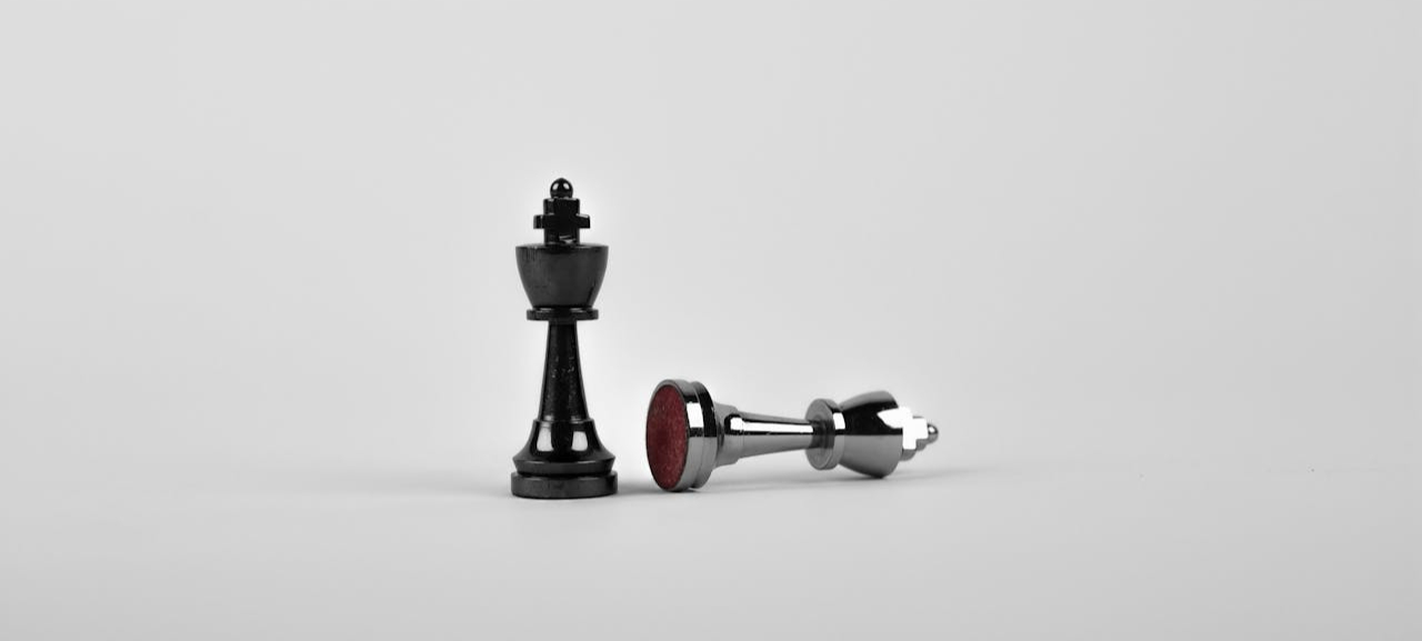 Two Silver Chess Pieces on White Surface